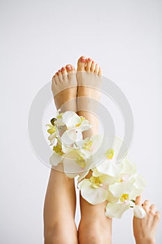 Hand and Nail Care. Beautiful Women`s Feet with Perfect Pedicure. Beauty Day The Girl Holding Orchid Flowers. Spa Manicure.