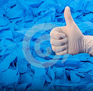 Hand in new white latex medical glove on background of a lot blue rubber gloves