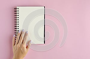 Hand with note pad composition on pink background