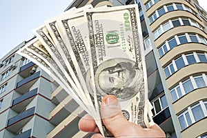 Hand with notes of dollars against the Residential building