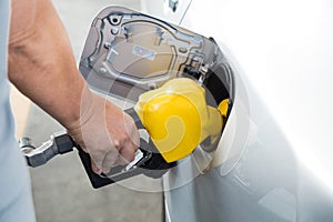 Hand with nozzle fueling unleaded gasoline into car