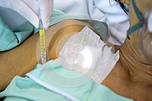 Hand of nurse in medical glove holding a glass thermometer,measuring fever,check body temperature under the armpit of senior