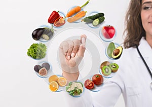 Hand of nutritionist doctor showing pill on symbols fruits photo