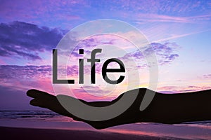 Hand offering the word life,sunset background