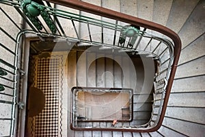 A hand on the old brown banister of a staircase