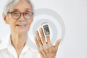 Hand of old elderly with fingertip pulse oximeter on finger for examination of the lung disease,checking for Coronavirus COVID-19