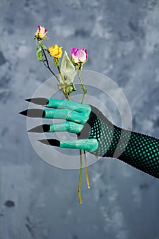 Hand of old green witch with dry roses - fairytale scene.