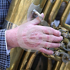 Hand of old man plays the trombone brass