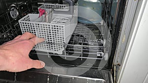 Hand open door and puts dirty dishes in the dishwasher. Modern dishwasher machine with plates