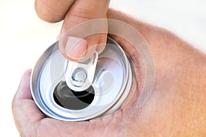 A hand opening a canned beverage.