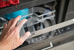 a hand opening a dishwasher, indoor closeup