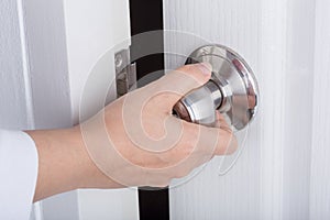 Hand opening door knob on white door