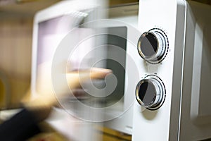 Hand opening a white microwave photo