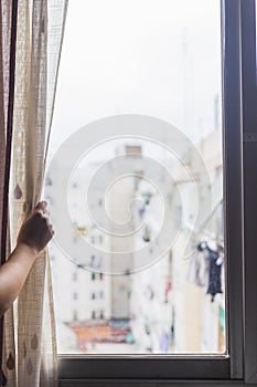 Hand opening window curtain of house photo