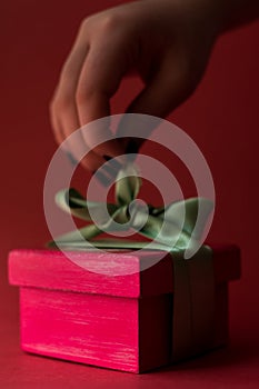 Hand openning a pink gift box with a green ribbon photo