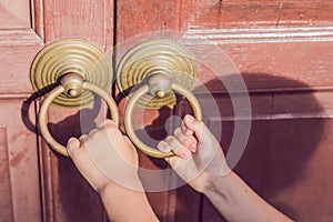 The hand opens the antique door by the round handle