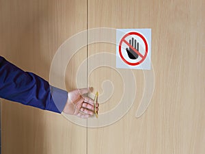 Hand opens door on which warning sign of ban, stop hand