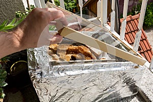 Hand opens homemade box for melting bees wax