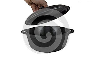 The hand opens the lid. Cast iron pan,  cast iron pot, empty, black. From the side