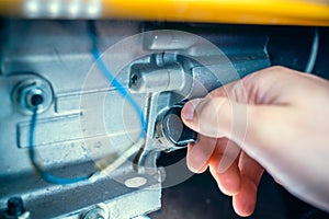 A hand opens the oil dipstick of a gasoline electric generator. Maintenance of an internal combustion engine