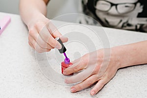 Hand opens a purple gel, gel nail manicure.