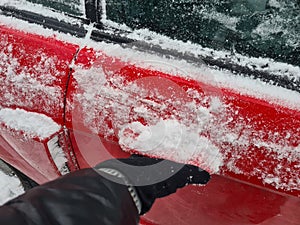 Hand opens snow covered car door handle from outside