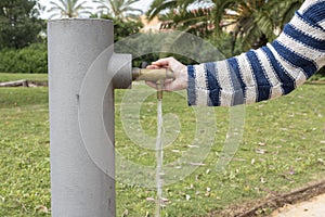 Hand opens the tap outdoors