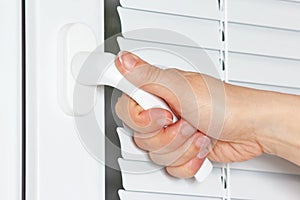 Hand opens the white plastic window with jalousie