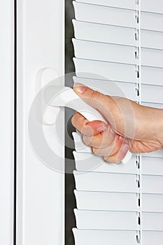 Hand opens the white plastic window with shutters