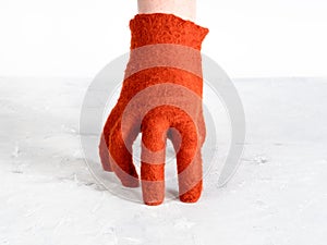 Hand in orange felted glove leans on gray board