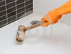 Hand in orange glove cleaning bathroom dirty floor