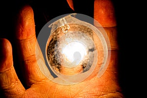 Hand and orange light bulb black background