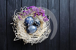 Hand painted dark blue easter eggs in nest and flowers