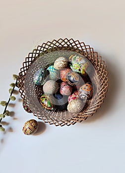 hand painted easter eggs in a basket with a willow brunch on white background. Traditional Painted egg in natural color