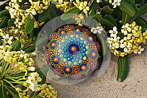 Hand painted mandala rock on sand