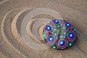 Hand painted mandala rock on sand