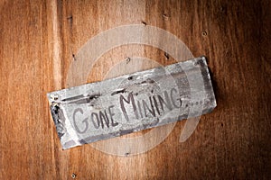 Hand painted sign on wooden door saying gone mining