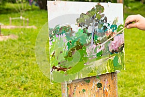 Hand of a painter holding a paintbrush in the open air