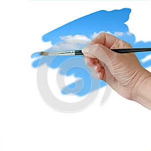 Hand painting blue sky with paintbrush