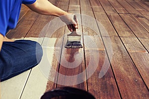 Hand and painting brush paint brown color on wood floor ,diy concept