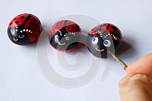 Hand painting three stones as cute ladybugs