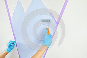 hand painting wall with paint roller and masking tape. Painting apartment, renovating with blue color paint