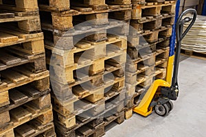 Hand pallet truck with stack of wooden pallets. Warehouse equipment. Transportation of goods in stock.Lifting equipment