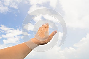 Hand palm on the blue sky with clouds