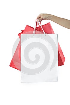 Hand with paper bags on the white background - studio shoot, shopping and consumerism concept