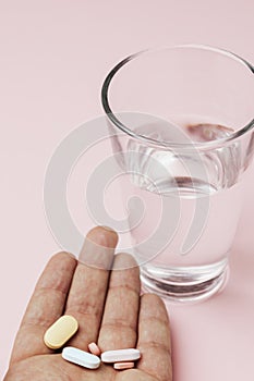 Hand of patient with pills and a glass of water