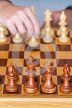 Hand with pawn makes first move on chess Board