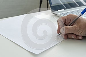 hand with a pen in close-up signs an empty paper document. A man fills a white blank paper form with a pen close-up in