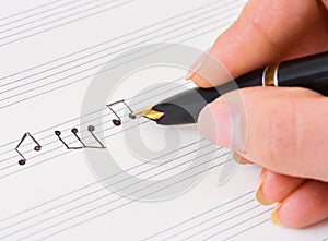 Hand with pen and music sheet