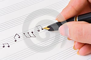 Hand with pen and music sheet